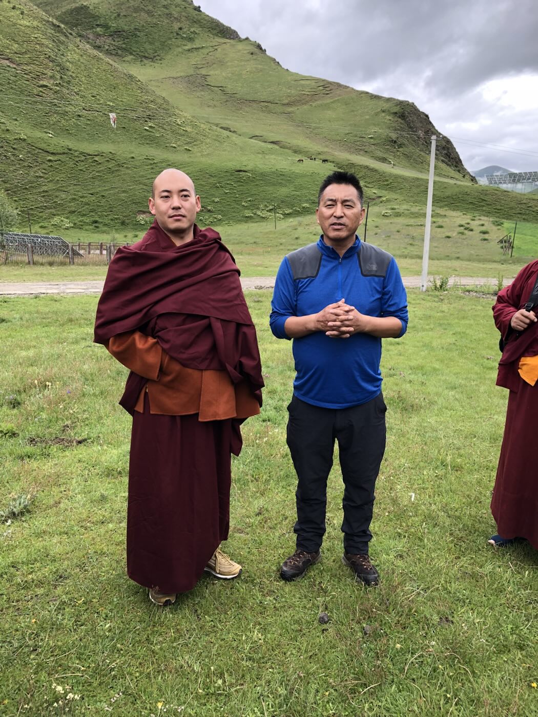 Two men standing in a field, one wearing a monk’s robes